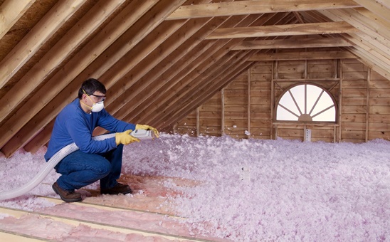 Technician installing blown-in insulation in an attic.
