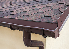 Dark brown gutters at the corner of a home's roof.