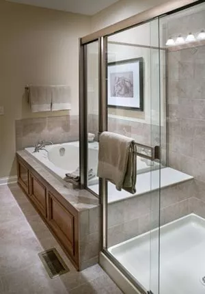 Framed glass shower door in bathroom with tan ceramic tiling